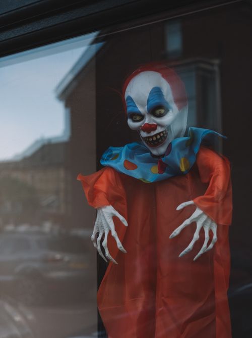 Free Scary clown figure with eerie expression seen through a window, perfect for Halloween themes. Stock Photo
