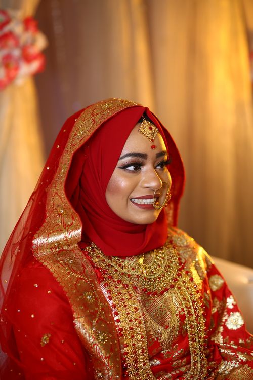 Free A beautiful Indian bride smiling in rich traditional attire, showcasing intricate jewelry and vibrant colors. Stock Photo