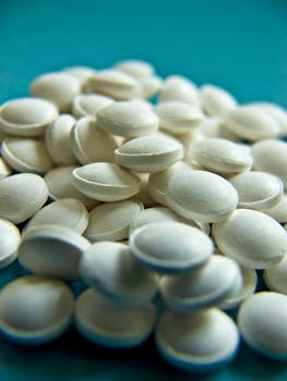 A detailed close-up photo of white tablets scattered on a blue surface.