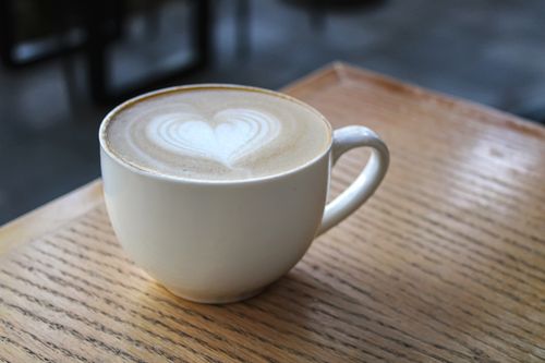 Free A close-up of a heart-shaped latte art in a ceramic cup on a wooden table. Stock Photo
