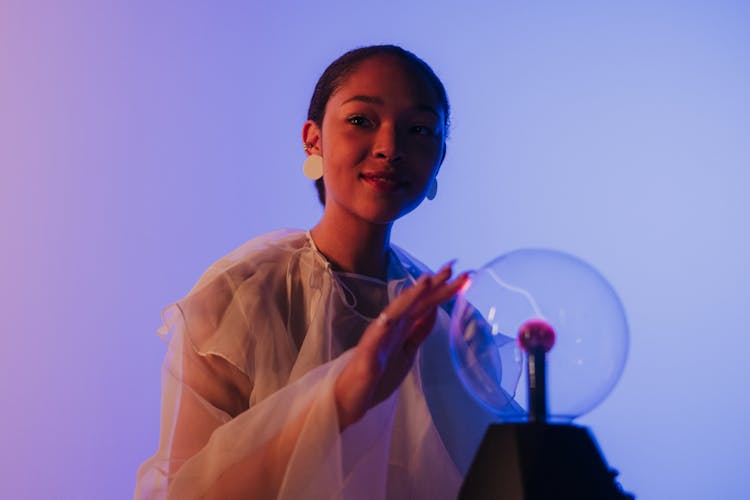 A Female Touching a Plasma Ball And Looking At Camera 