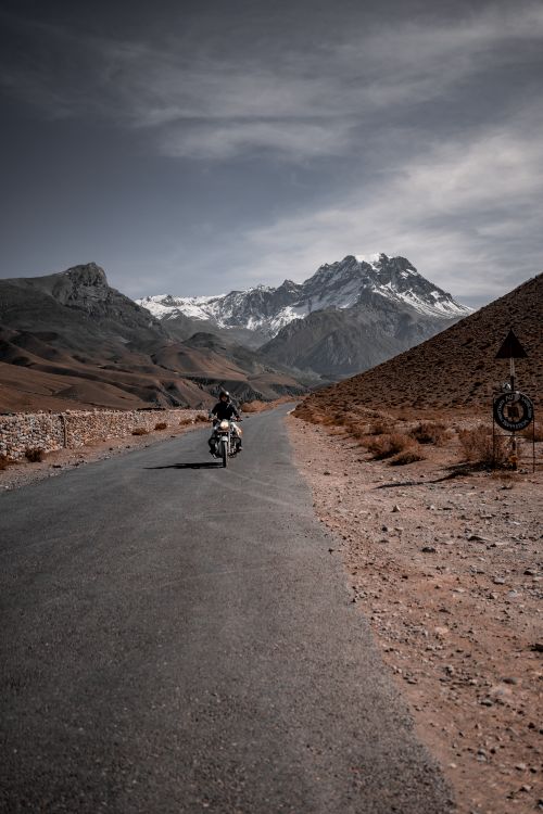 Free A motorcyclist travels along a winding road through stunning mountainous scenery. Stock Photo
