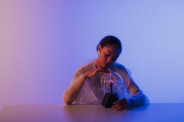 Woman Touching Magnetic Ball On Table