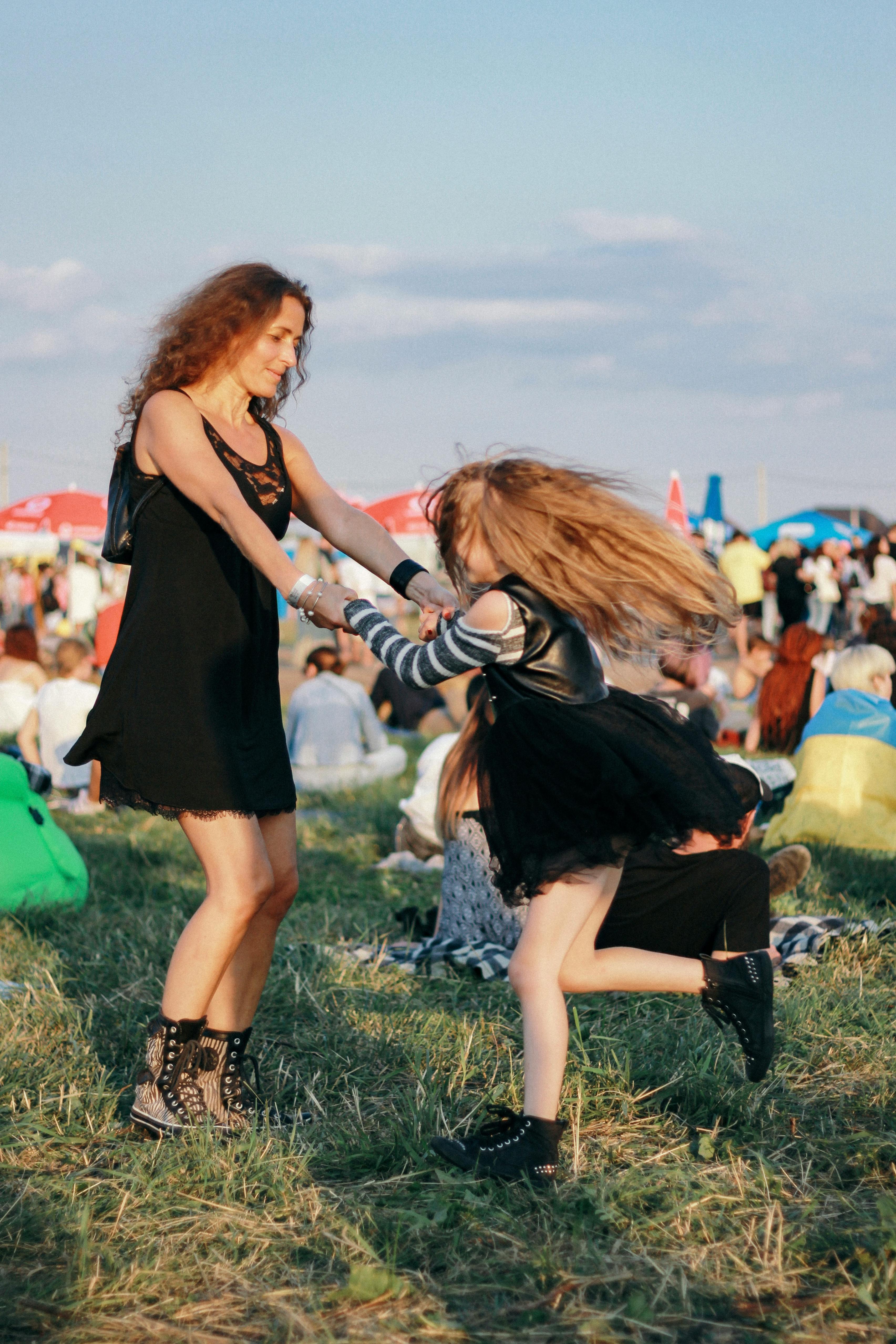 Joyful mother and daughter dancing together in a lively outdoor festival scene.