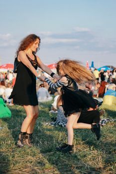 Joyful mother and daughter dancing together in a lively outdoor festival scene.