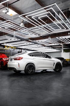 A white sports car parked in a futuristic urban garage with unique ceiling lights.