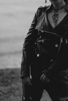Black and white photo of an adult woman in a leather jacket by the water.