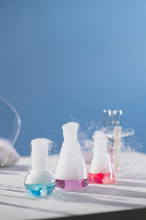 Free A vibrant laboratory scene with steaming flasks showcasing colorful liquids against a blue background. Stock Photo