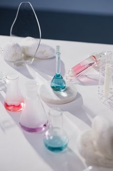 Various colored liquid-filled flasks on a table under bright lighting, showcasing a chemistry experiment setup.