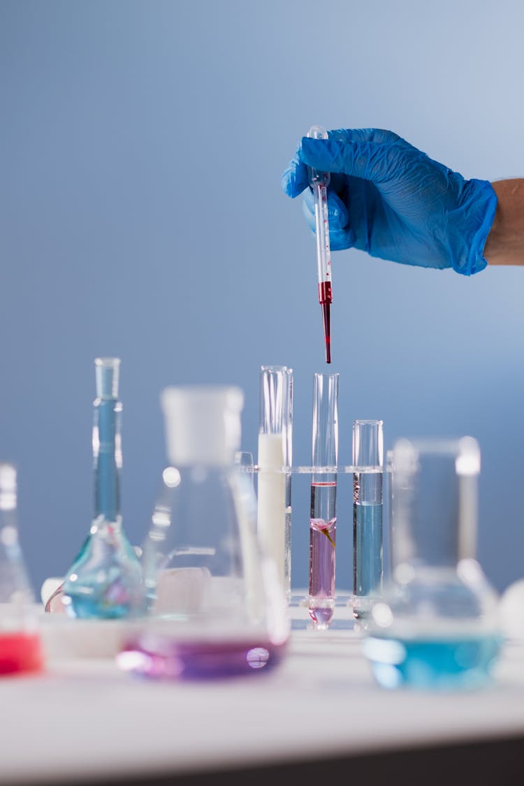 Hand In Glove Adding Liquid To Test Tube