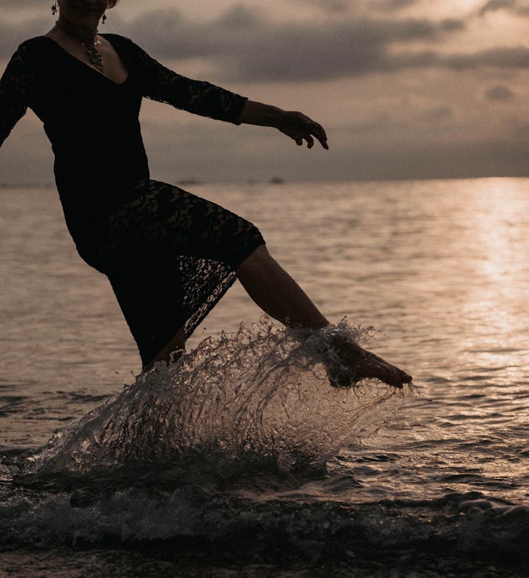 Woman In Black Dress Kicking The Water