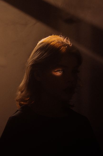 A mysterious portrait highlighting one eye in dramatic shadows and light.