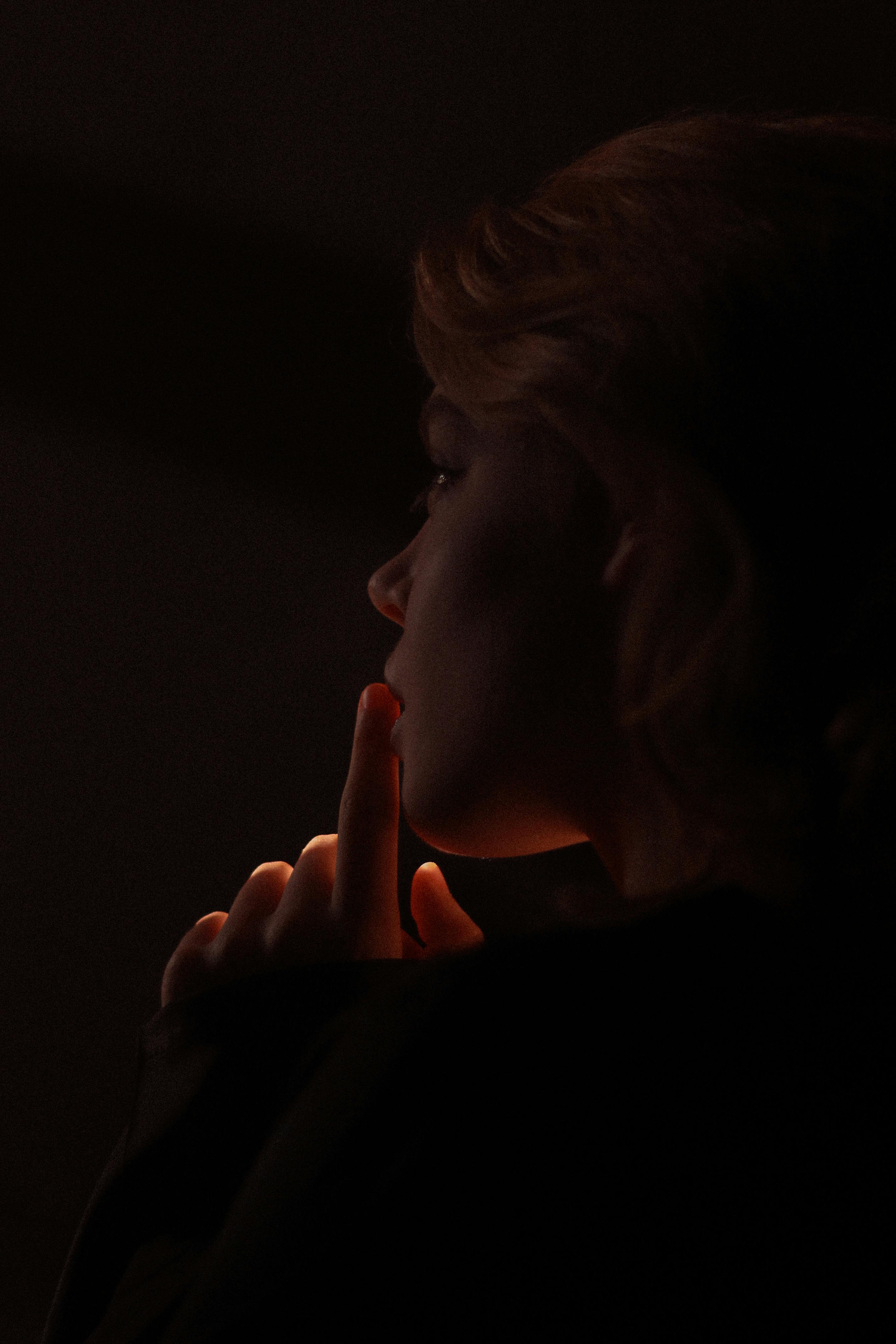 Artistic side profile portrait of a woman in low light, exuding mystery and contemplation.