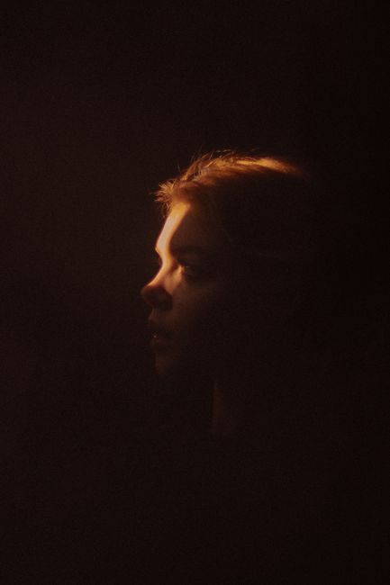 Profile view of a woman artistically lit against a dark background.