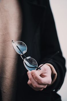 Close-up of a stylish hand holding elegant round eyeglasses.