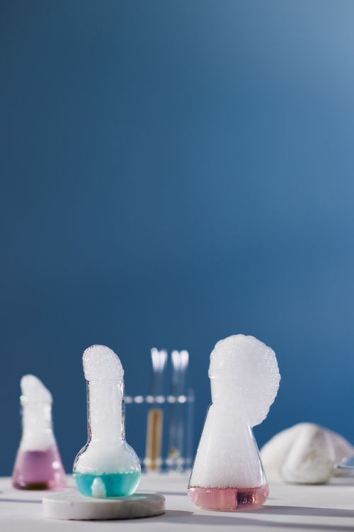 Free Bubbling chemical experiment with colorful liquids in laboratory flasks on blue background. Stock Photo