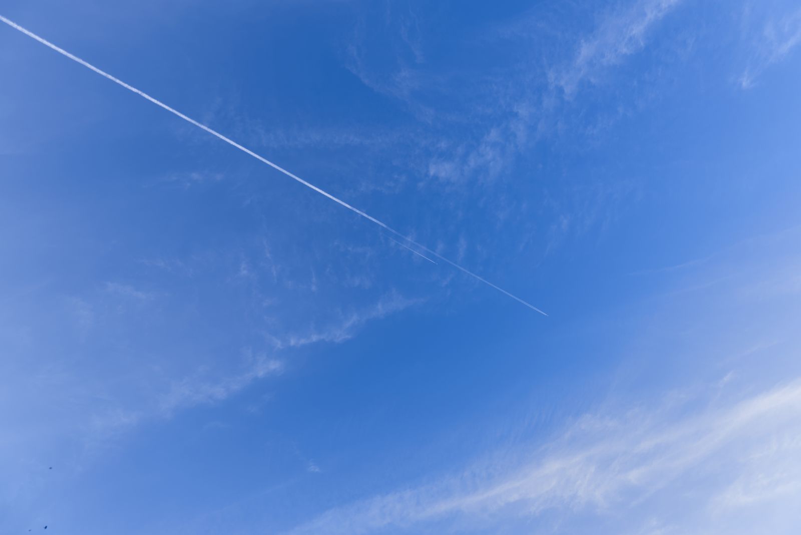 Traînée d'avion unique dans un ciel bleu dégagé aux nuages légers