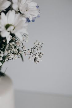 Beautiful close-up of wedding rings entwined with baby's breath flowers in a minimalist arrangement.