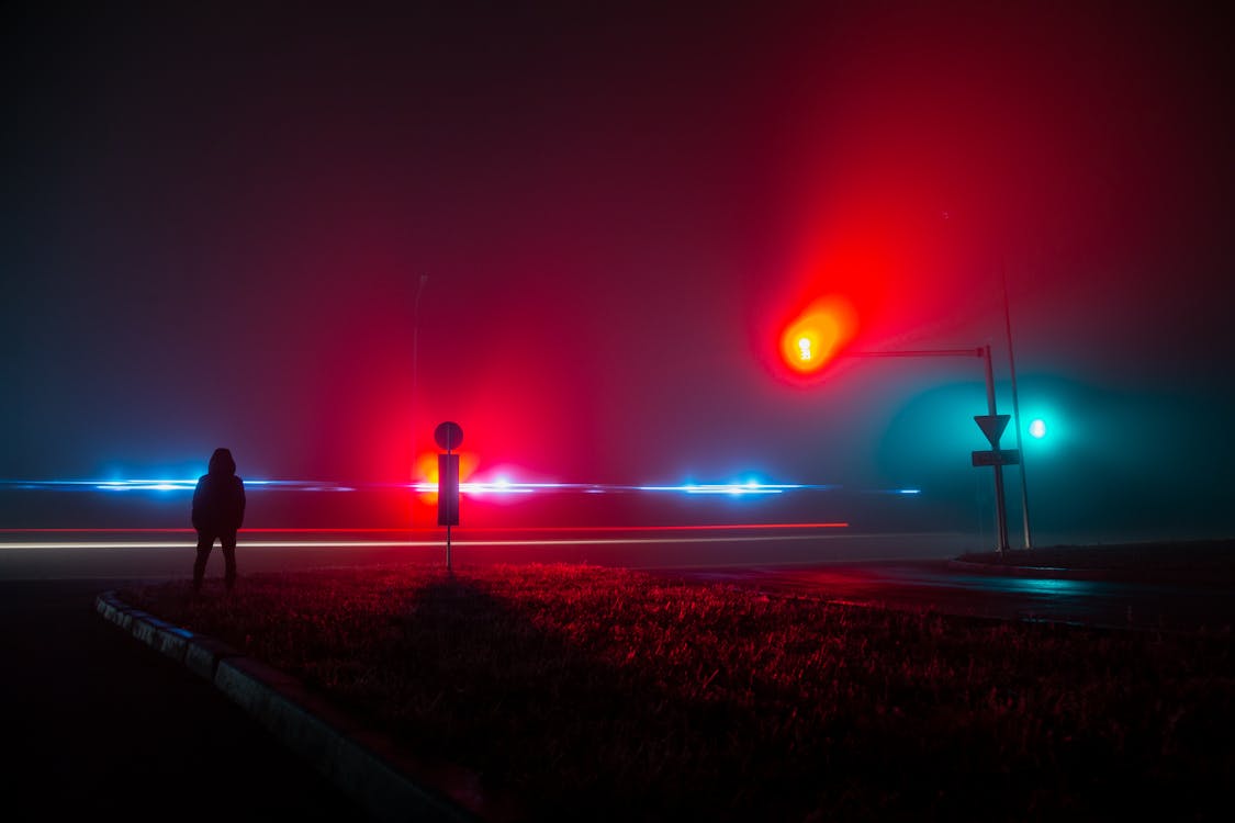 Free Unrecognizable Person Observing Red and Blue Lights on Road at Night Stock Photo