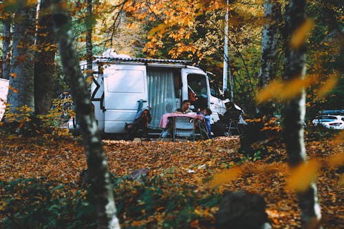 Free Man Sitting Beside a Camper Van with a Child Stock Photo