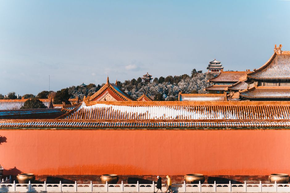 Snow-covered roofs of historical Chinese architecture under clear skies.