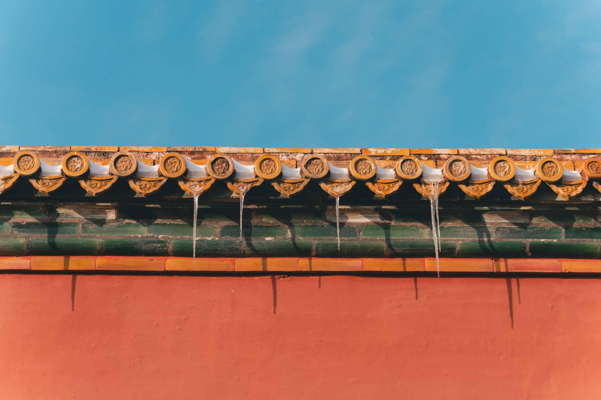 Ornate roof with icicles against a clear winter sky, showcasing traditional architecture.