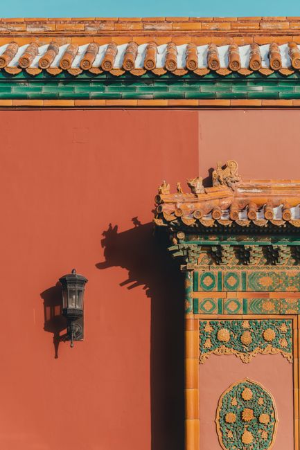 Intricate design of traditional Chinese architecture in Beijing featuring a red wall and ornate decoration.
