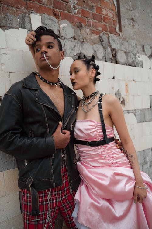 Free Man in Black Jacket and Plaid Pants Standing Beside a Woman in Pink Tube Dress with Black Lipstick Stock Photo
