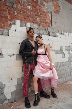 Couple in punk fashion against an urban brick wall, showcasing unique style and attitude.