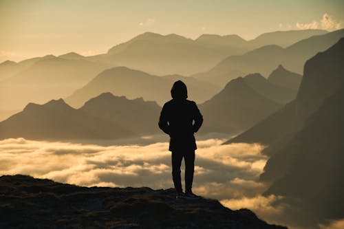 Silhouette of Man Standing on Top of Mountain
