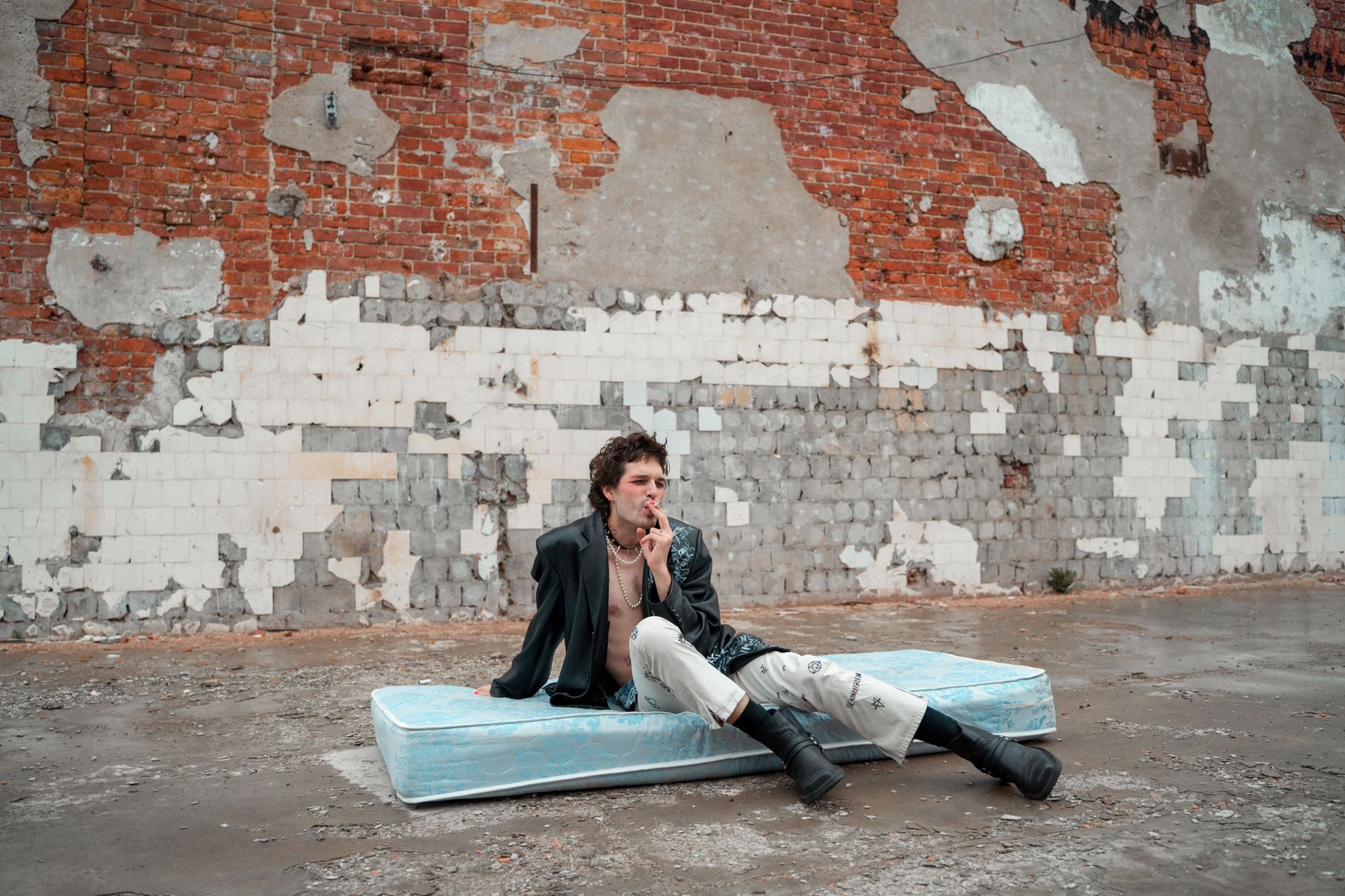 Man Sitting on Mattress on Street