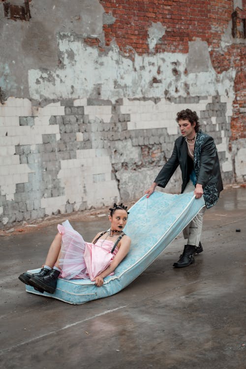 Free Man Dragging Woman on Mattress on Street Stock Photo