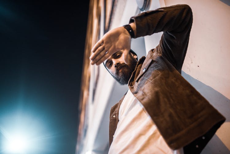 Bearded Man Standing By Building Facade At Night