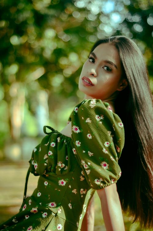 Free Portrait of a woman in a floral dress posing gracefully outdoors. Stock Photo