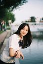 Young Woman with Long Black Hair Standing by Railing at Riverside