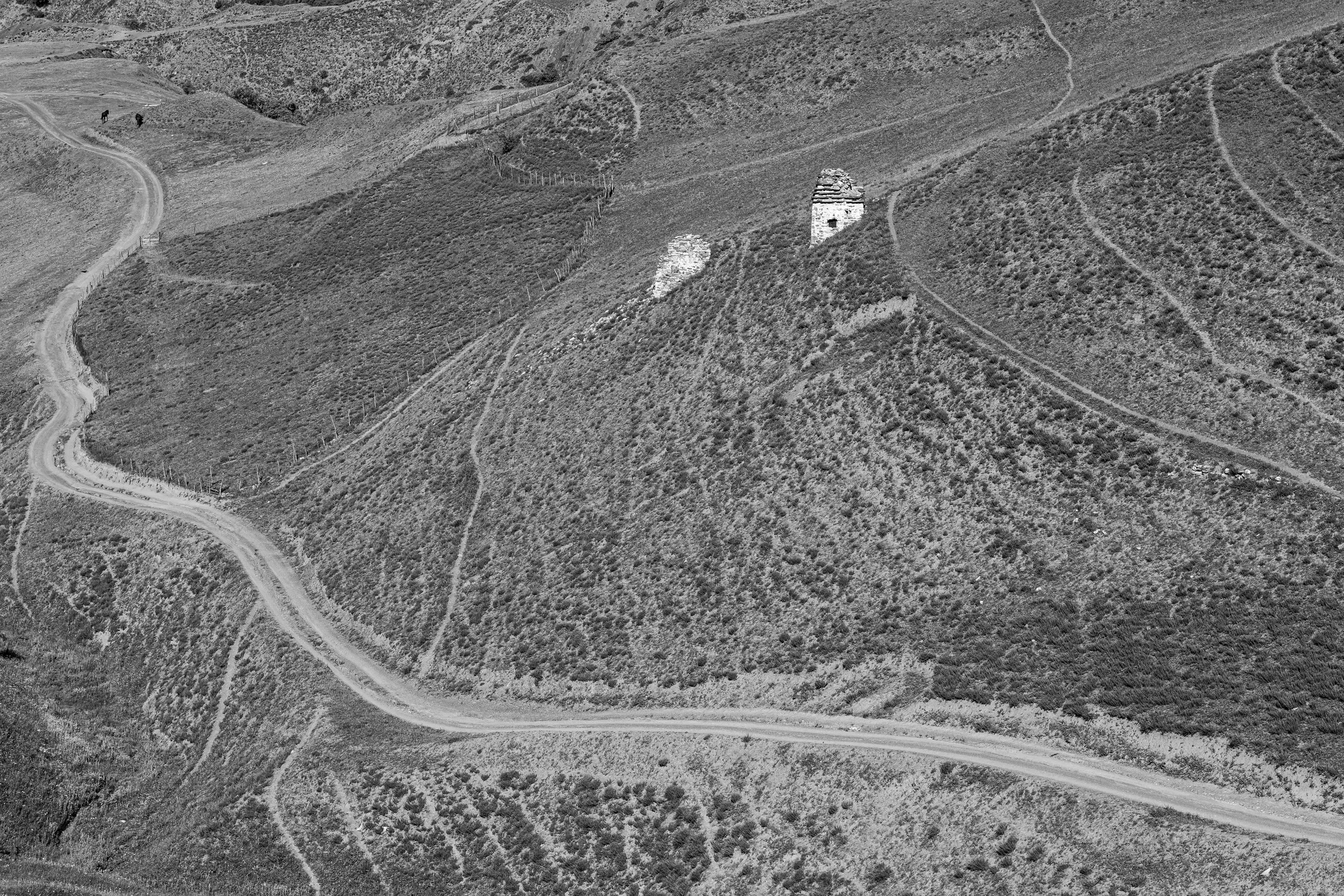 Gravel road winding between dry hills in southern La Paz department