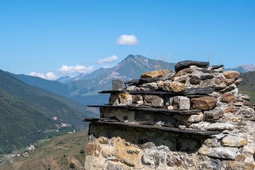 Free View of ancient stone ruins with majestic mountains under a clear sky. Stock Photo