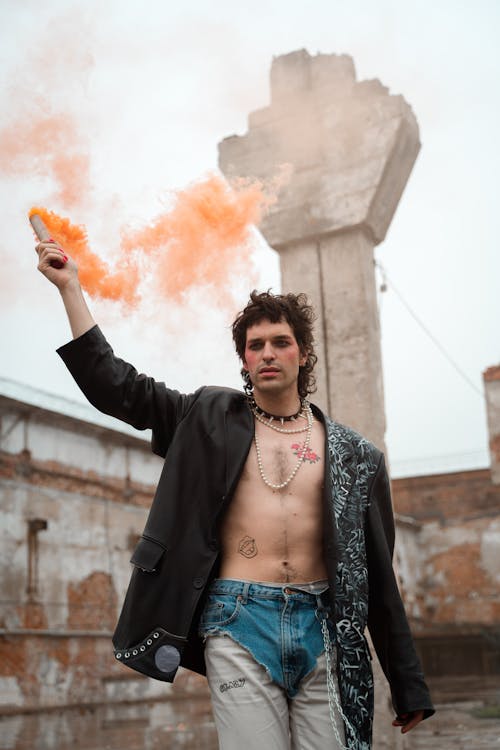 A Man Holding a Smoke Bomb While Standing Near the Concrete Structure