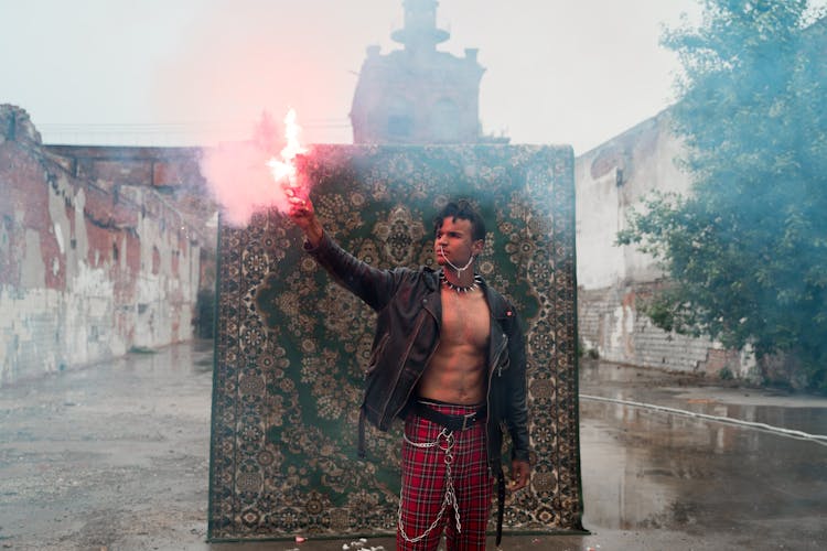 Man Holding A Road Flare In Front Of A Rug