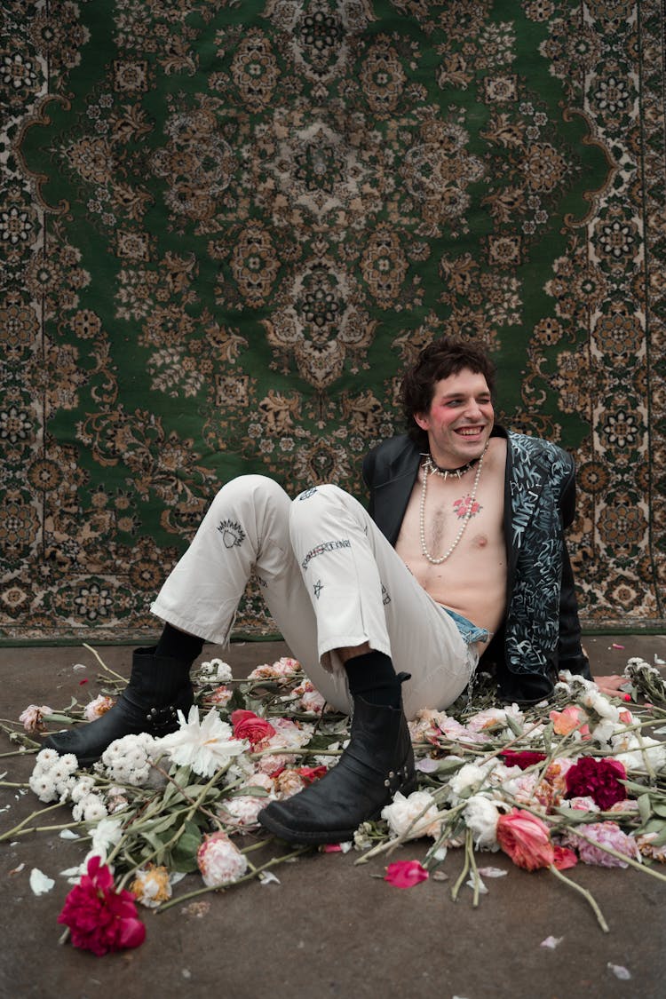 A Man With Unbuttoned Jacket Sitting On Floor With Flowers