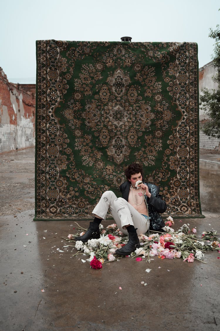 A Man Sitting On The Ground With Scattered Flowers