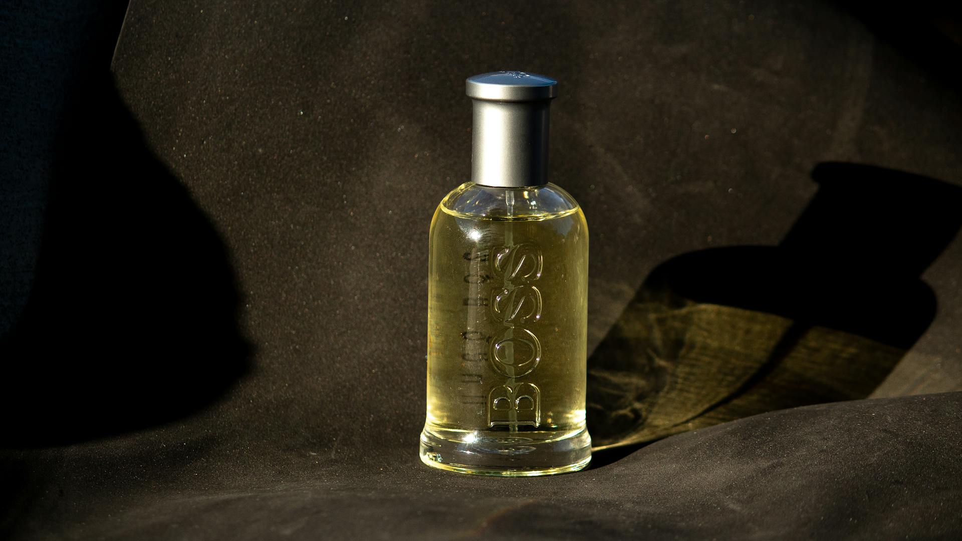 Sophisticated perfume bottle with embossed text elegantly showcased on dark fabric backdrop.