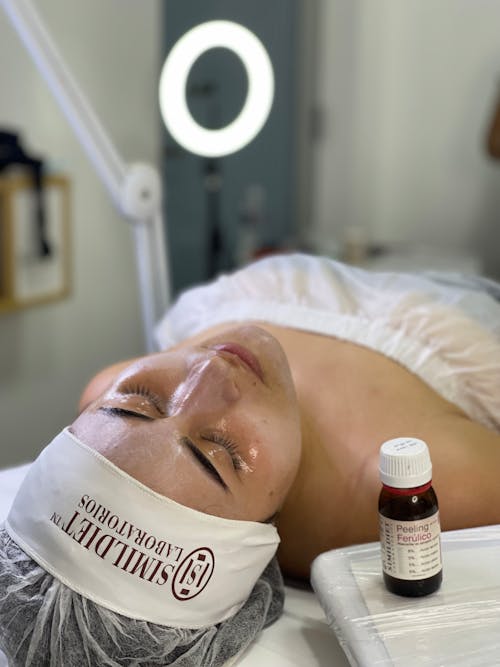 A Woman Lying on Spa Bed with a Peeling Solution on Face