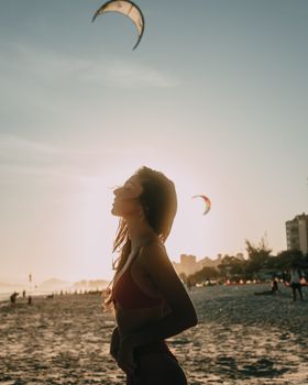 Woman enjoying a serene sunset on Ipanema Beach, Rio de Janeiro, with kites in the background.