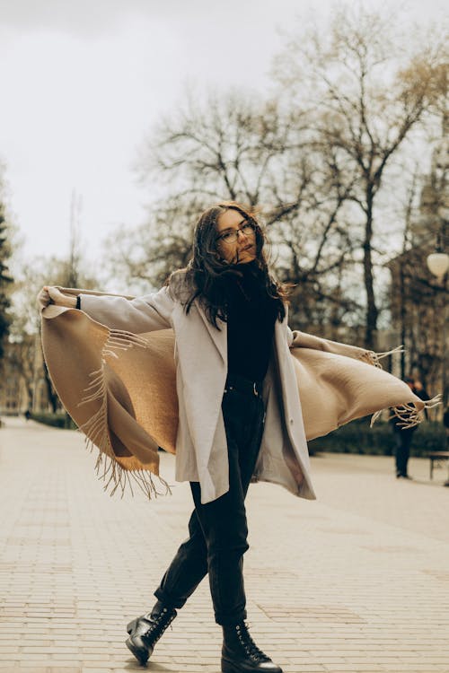 A Woman in Beige Coat Holding a Brown Shawl