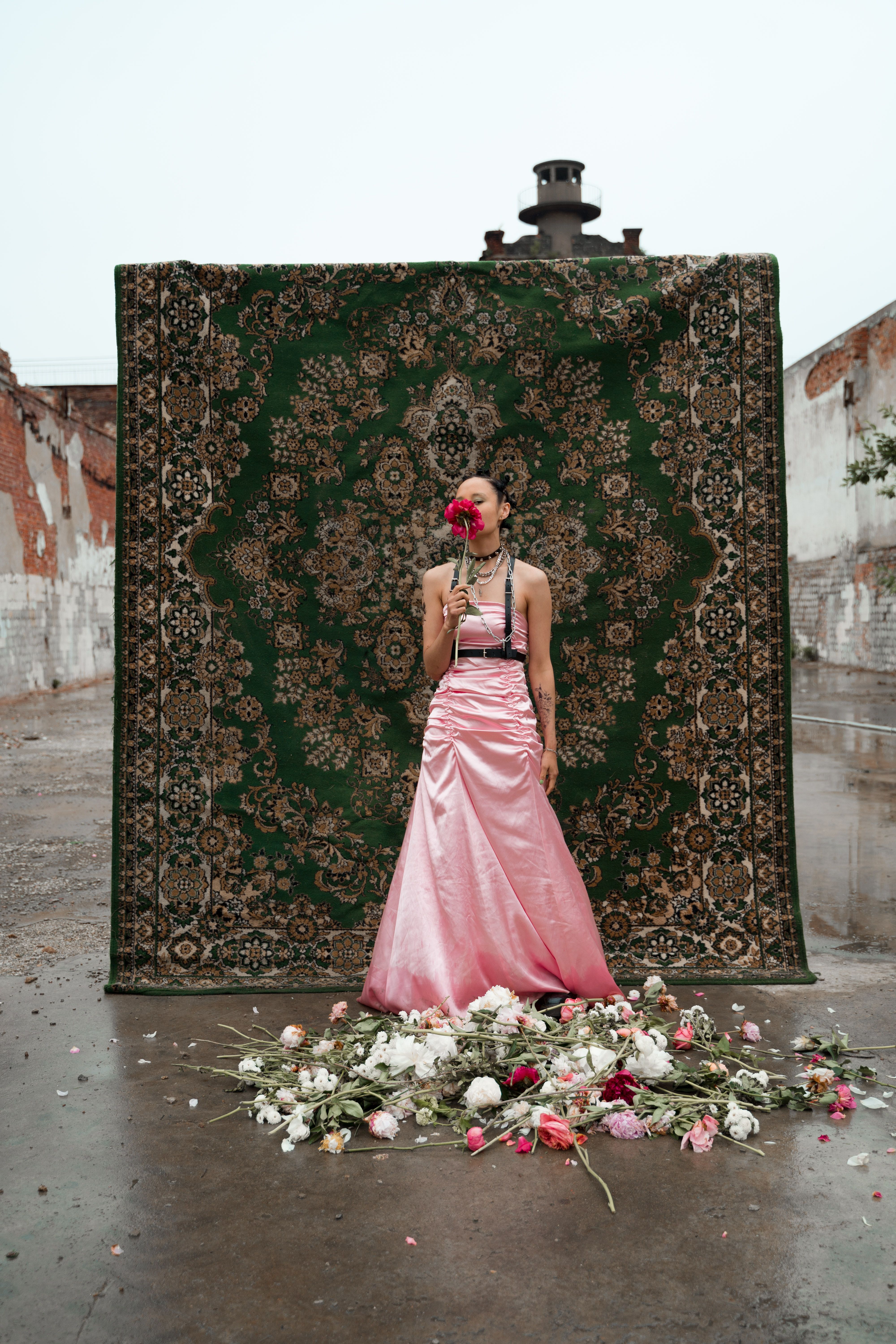 A Woman in Pink Dress Standing while Holding a Flower · Free Stock Photo
