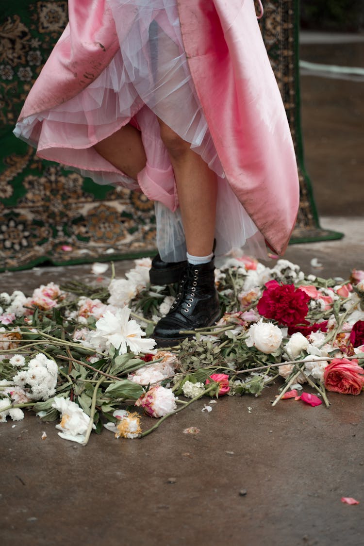 Person Wearing Black Boots Stepping On Flowers