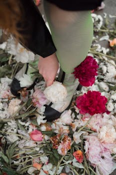 A person in chic shoes and stockings amidst vibrant floral petals, a stylish fashion statement.