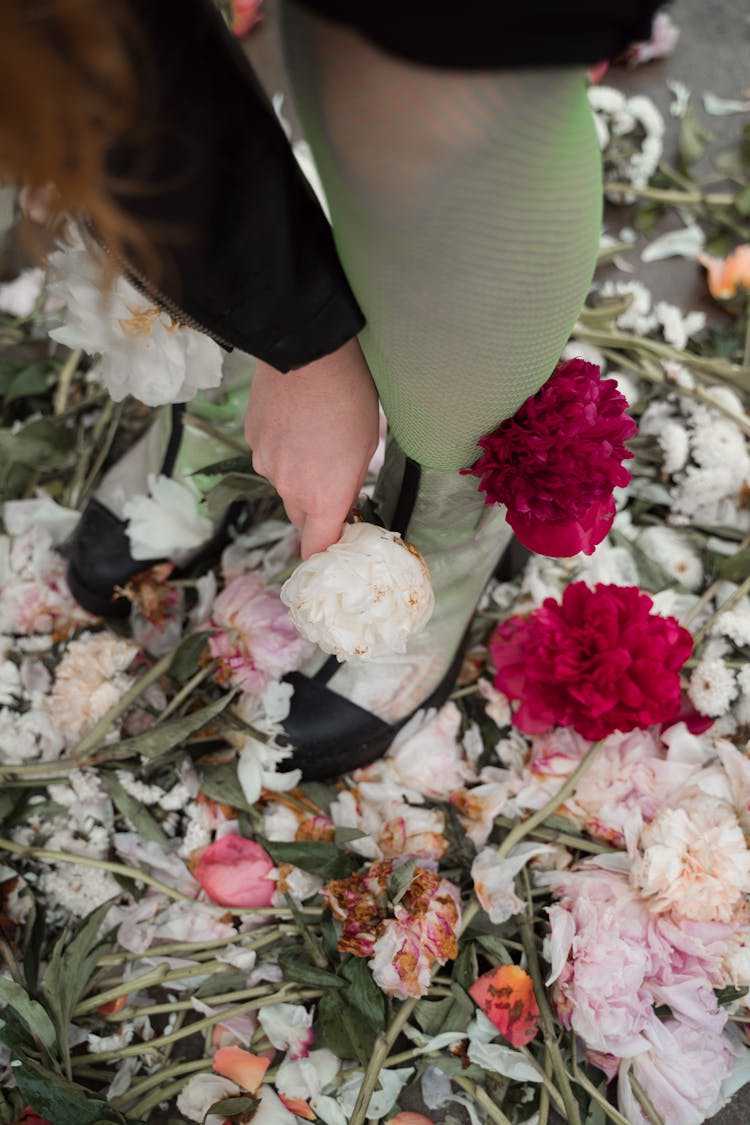 Person Holding Bouquet Of Person Putting Flowers On Shoes 