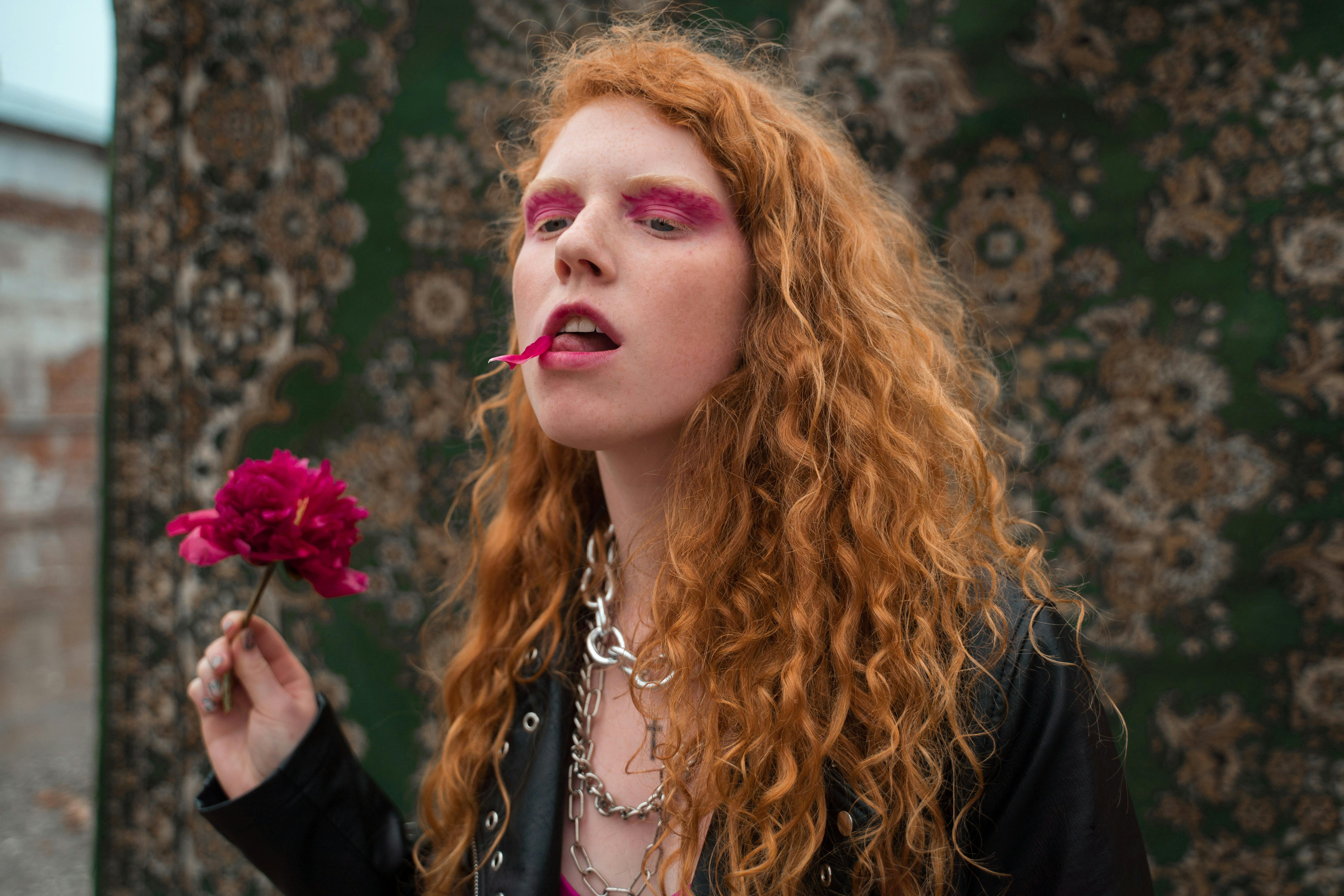 a woman in leather jacket with a petal on her mouth